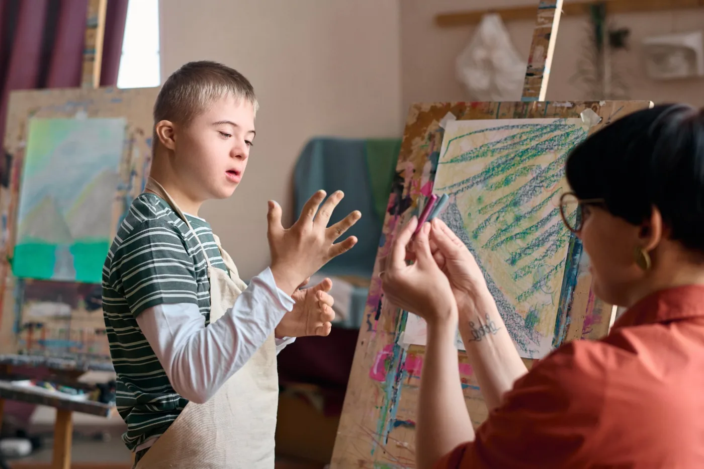 Boy with Down syndrome choosing paint colours in art session with specialist support worker