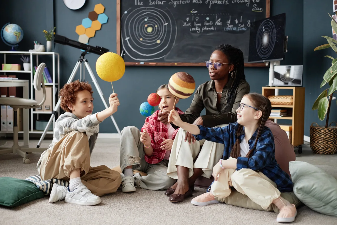 Children and teacher exploring solar system models together