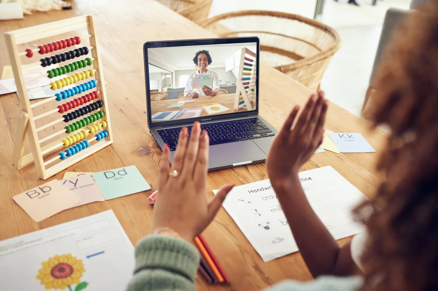 Parent and child waving to teacher during online learning session at home