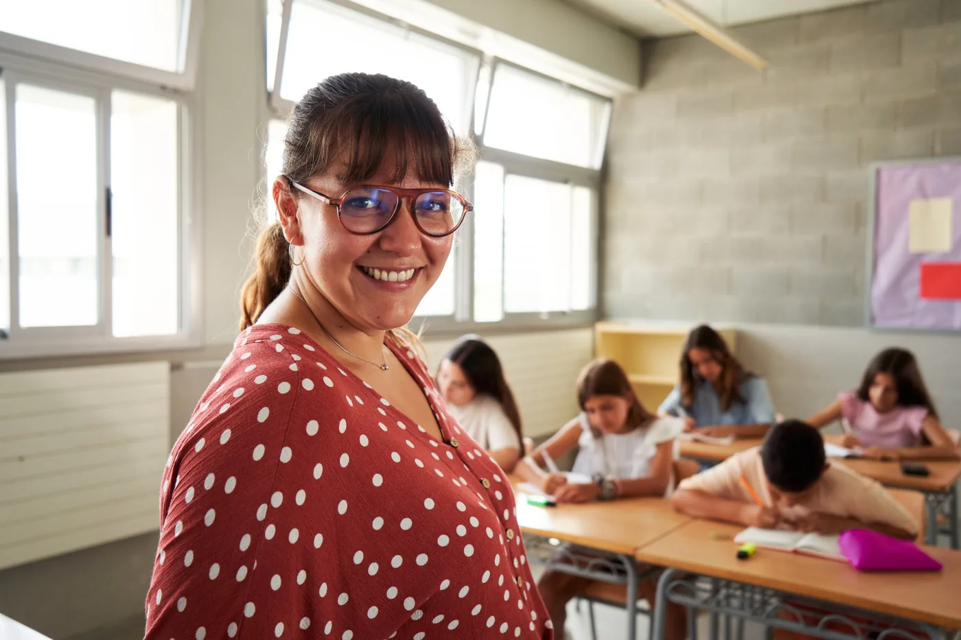 Smiling teacher with pupils working in the background