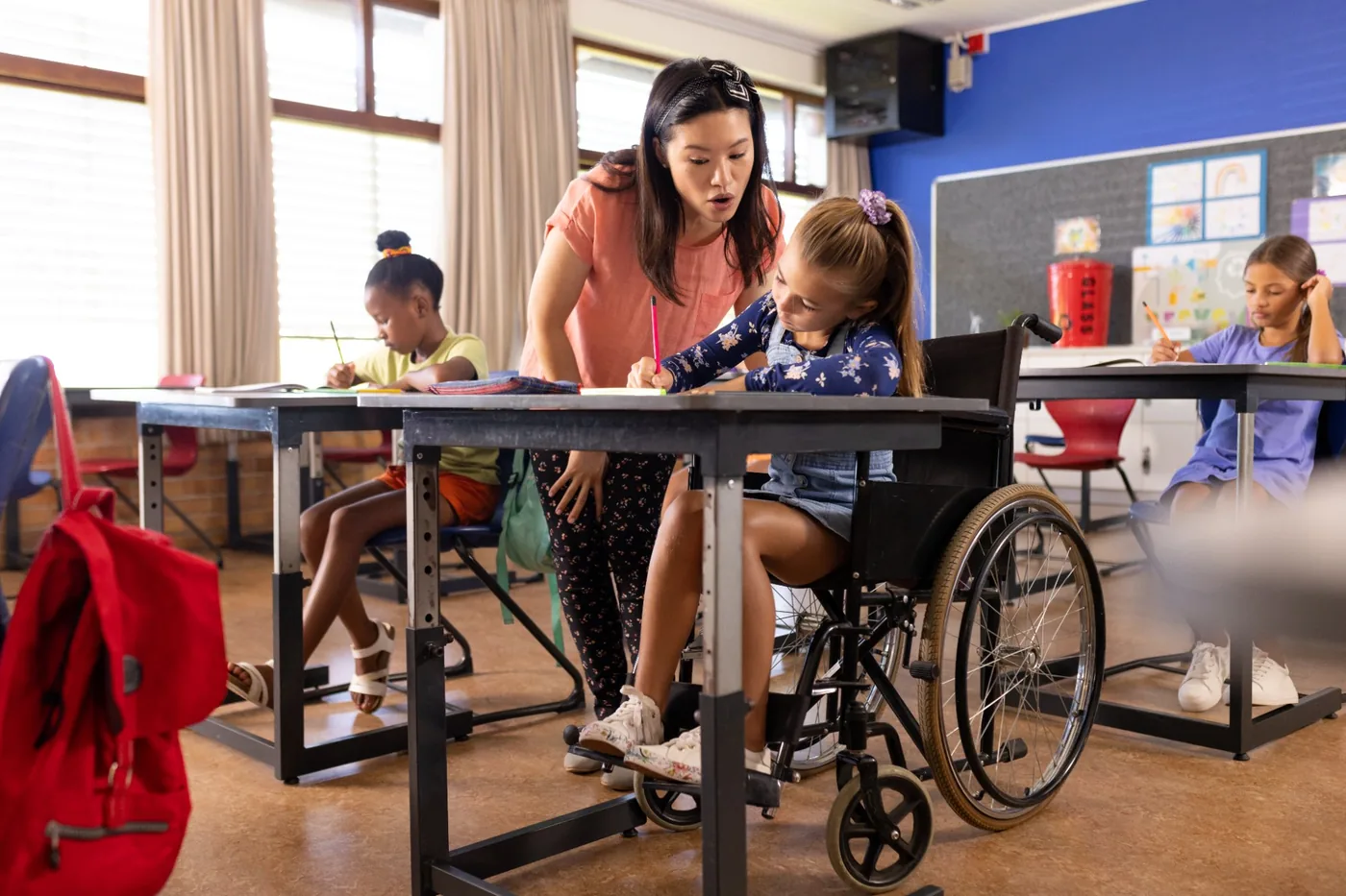 Teacher assisting a girl in a wheelchair in an inclusive classroom